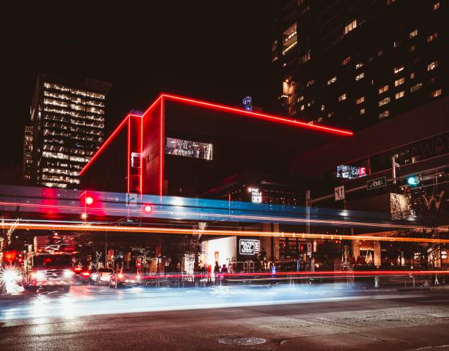 Extierior of ACL Live at the Moody Theater lined by red neon lights, illuminated by blurs of light on the street below.
