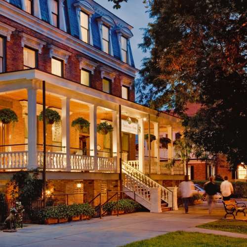 View of front porch from sidewalk at dusk, porch lit up.