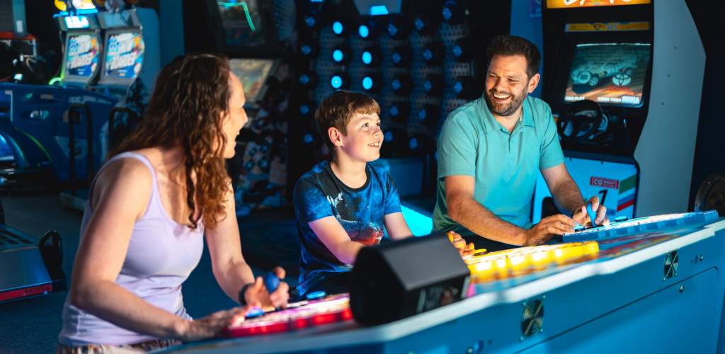 Family playing arcade game and smiling at each other