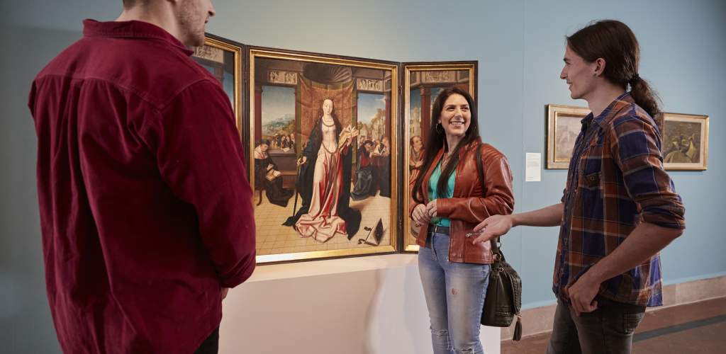 Group standing in front of a painting of a woman discussing artwork at Southampton City Art Gallery
