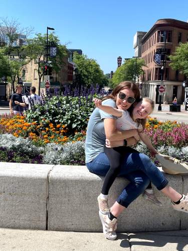 A woman and daughter pose by flowers at the Top of State Street