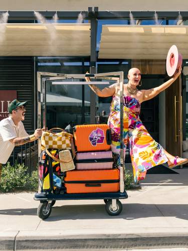 Two people pushing a travel cart in front of the Thompson Hotel in Palm Springs