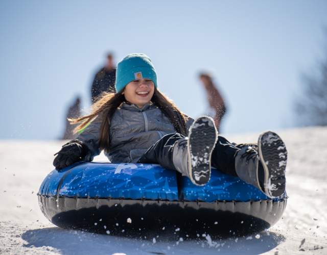 girl on sled going down snow hill