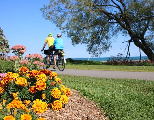 Mariner's Trail couple on tandem bike with orange flowers in foreground