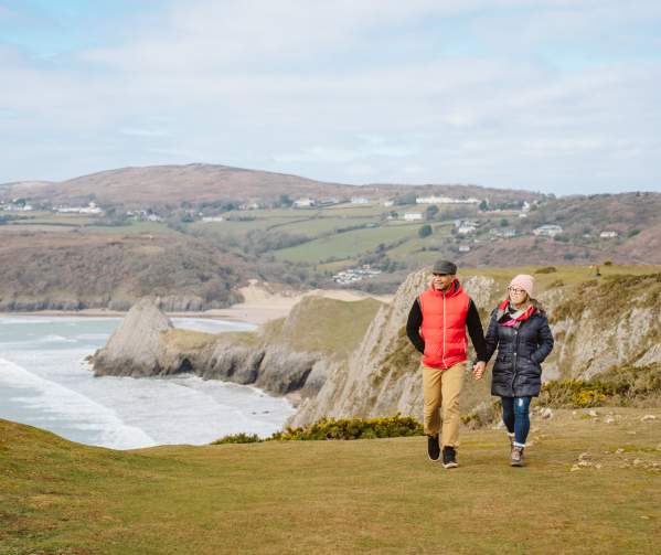 A couple walking across Three cliffs in the winter