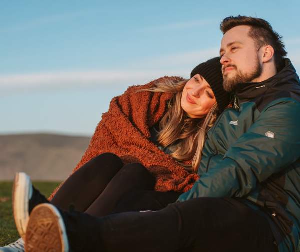 A couple (man and woman) in winter clothes watching a sunset.