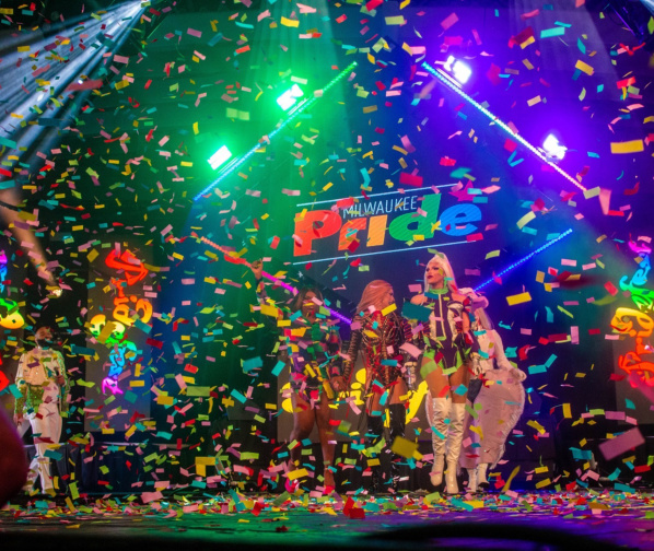 A group of drag queens performing onstage at Pridefest in Milwaukee as party streamers fall around them