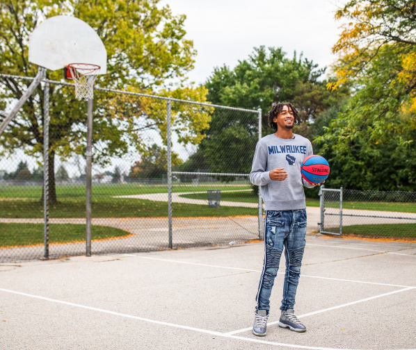 Learic Davis on an outdoor public basketball court, smiling and holding a basketball