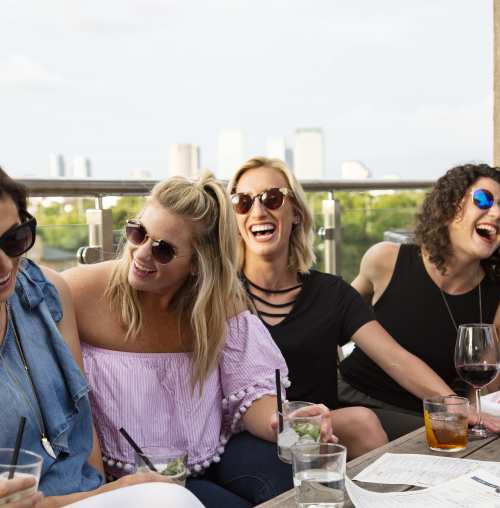 Row of women laughing over drinks