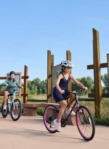 Family Biking outdoors on the Poudre River Trail with sign behind them