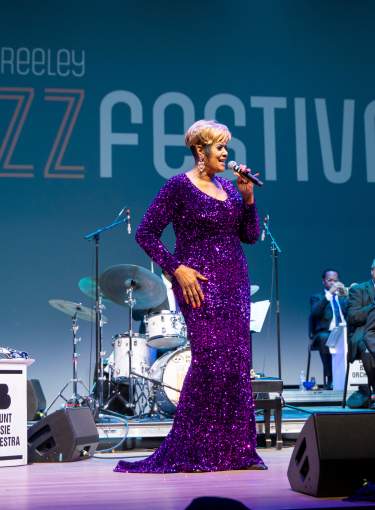 Women in purple dress singing with jazz band in the background at UNC Jazz Fest 2025