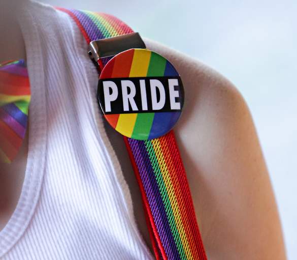 Person wearing pride pin and suspenders at Saratoga Pride Festival