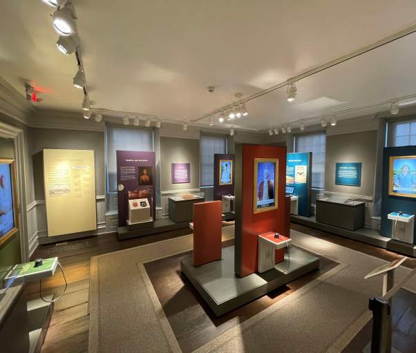 An exhibit inside Philipse Manor Hall showing portraits of historical figures.