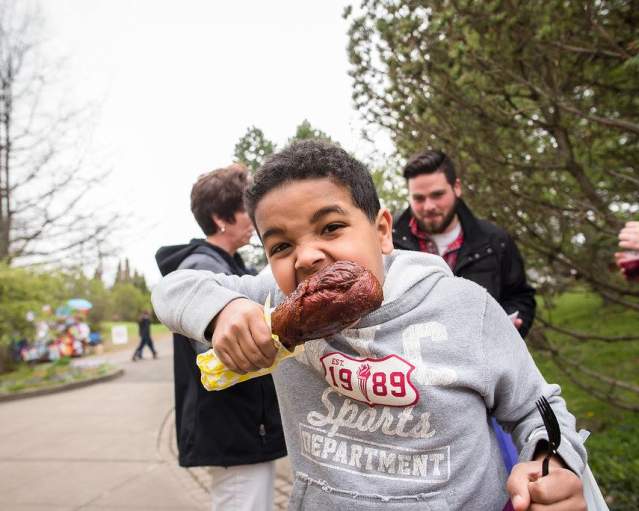 boys bites into a turkey leg at the Rochester Lilac Festival