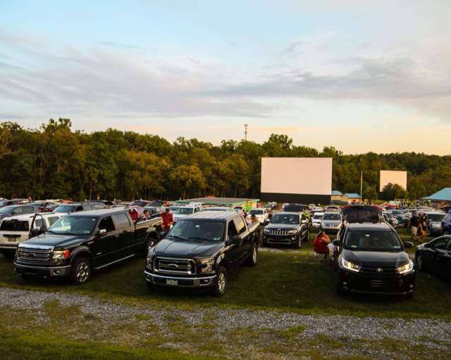 Cars parked in front of a field with a large projector