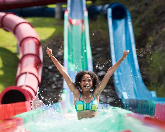 A young girl exits water slide with splashing water
