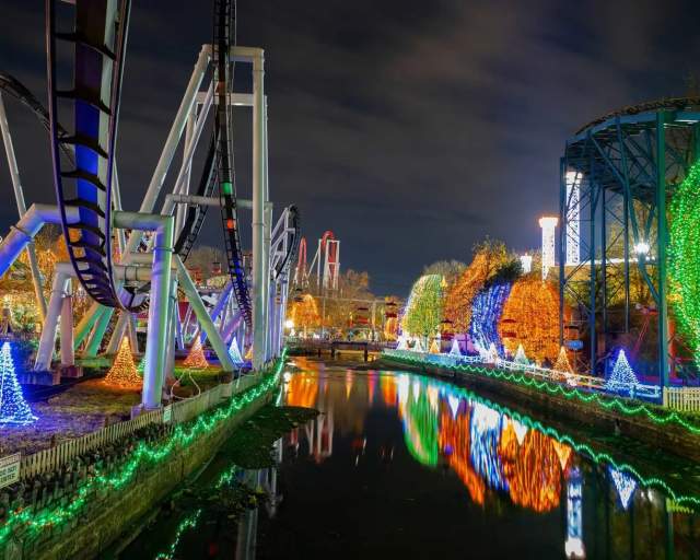 Hersheypark rollercoasters at night with decorated and lit Christmas trees throughout