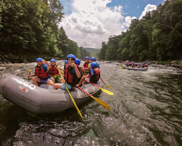 A group of people in helmets floating down a river in rafts