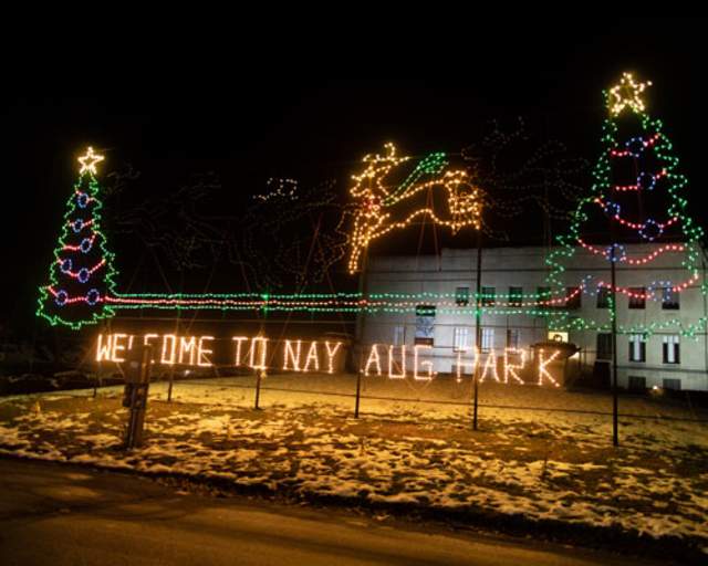Holiday lights at night decorating trees and spelling out "Welcome to Nay Aug Park"