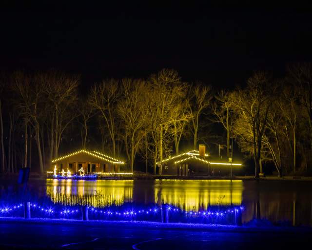 A small house on a lake in Erie at night that is lit up by holiday lights
