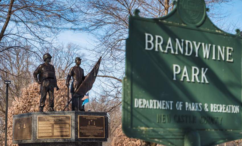 Bronze sculpture of two African American soldiers in the background, with Brandywine Park sign in the foreground