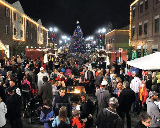 Group of People on main street with holiday lights around Christmas Tree