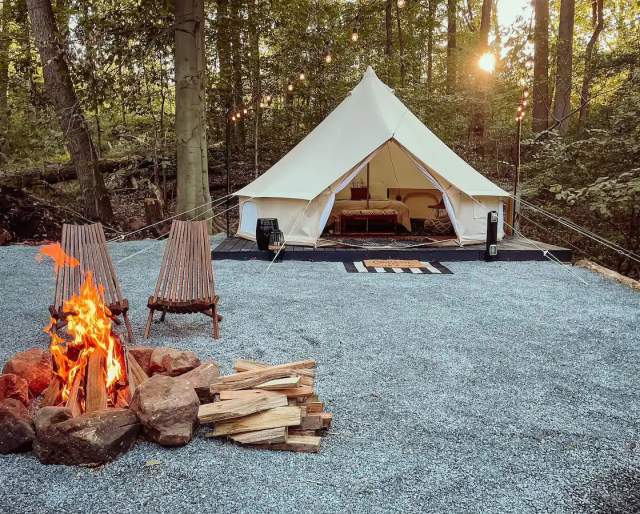 A glamping tent with a lit fire and chairs in front