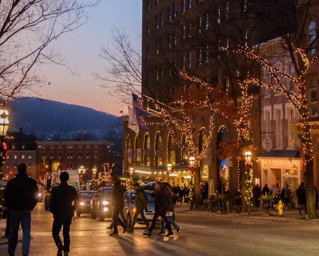 People walking through downtown Bethlehem during the holidays with holidays lights being displayed on buildings.