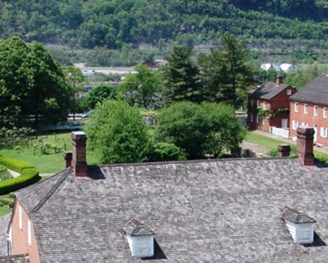 Aerial view of five red brick buildings with white trimming and a garden with a clear path and a fountain in the middle.