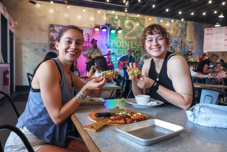 Two girls enjoying pizza and live music at the 12 Points Market First Friday event