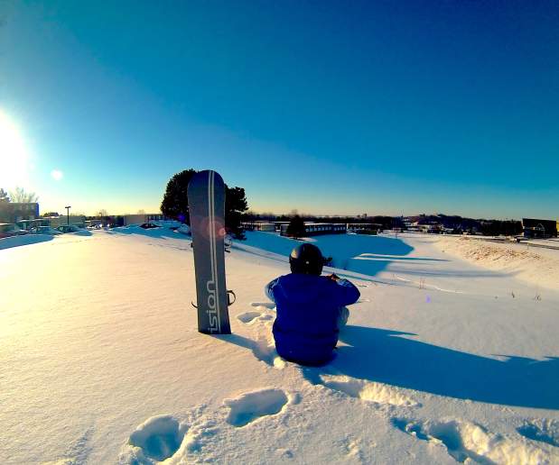 Snowboarder sitting on Syracuse University hill top