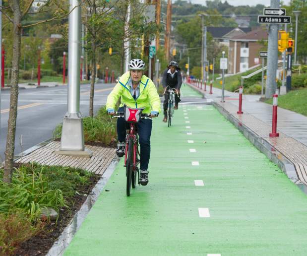 Man Rides Bike with Helmet in Green Bike Lanes Through Syracuse