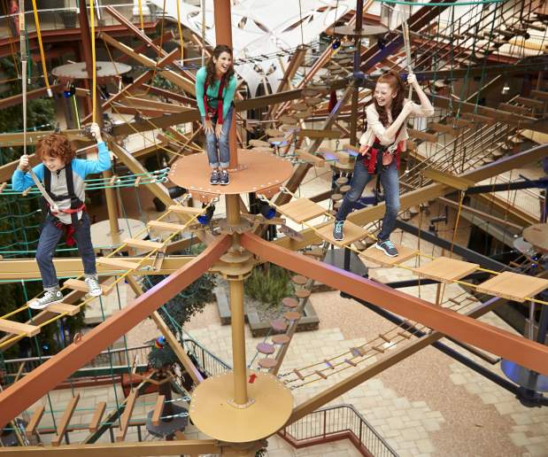 Ginger children playing on a ropes course suspended 3 feet above the air