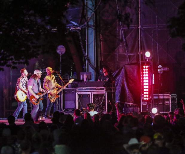 Night Shot of Band Singing and Playing Instruments in Outdoors Concert in Front of Crowd