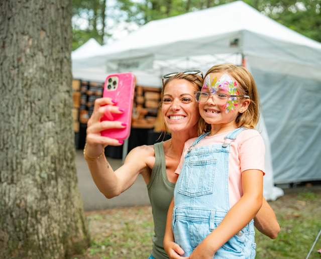 Mother taking a photo with her daughter at a festival