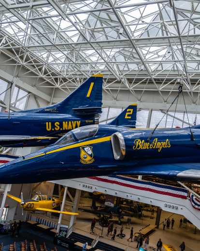Two Blue Angels planes hanging from the ceiling on display at the National Naval Aviation Museum