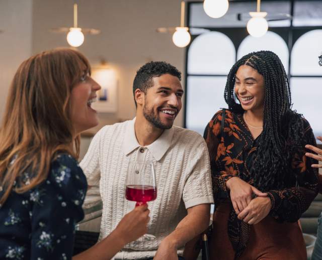 4 people in business casual dress smiling and laughing and talking to each other