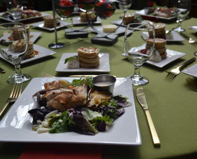 Chicken salad on square plates set on a green table cloth with utensils and dessert