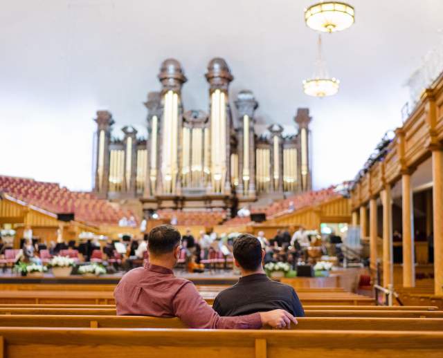 Two men sitting in the benches at the tabernacle with the historic organ in the background