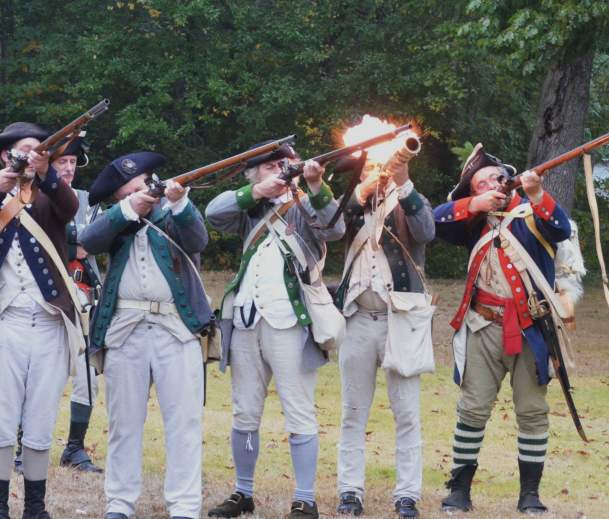 A group of historical Revolutionary War reenactors firing away at a Revolutionary War demonstration on Long Island.