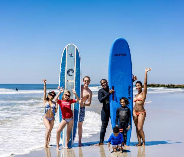family with kids surfing at the beach