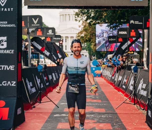 Athlete cheering while crossing the IRONMAN race finish line
