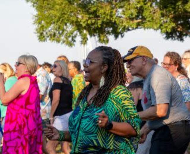 Group of partiers dancing outside to live music under a tree