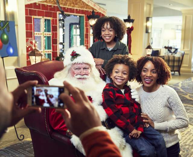 Father taking picture of family with Santa