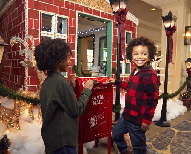 Children dropping letters to Santa Clause in holiday mailbox