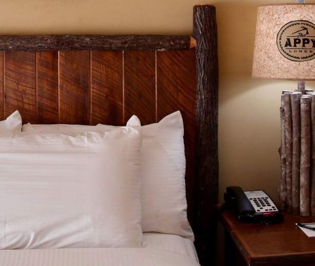 Hewn logs trim the headboard of a bed at the The Appy Lodge in Gatlinburg, TN.