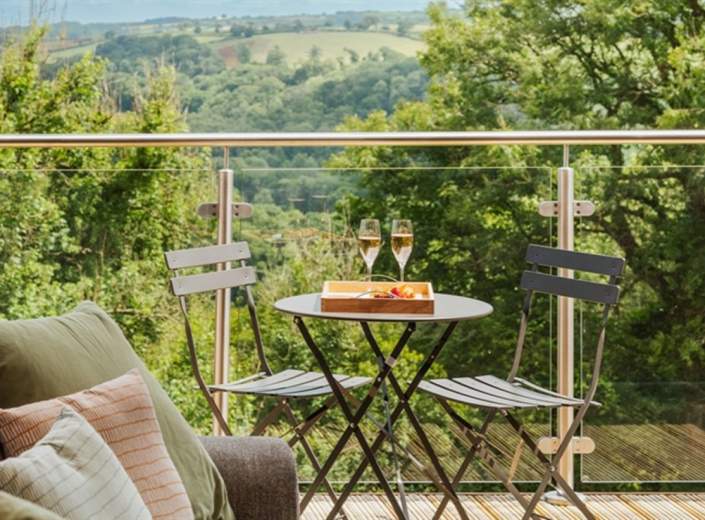 two glasses of champagne sat on a table, with two chairs facing each other on a balcony at The Mole Resort