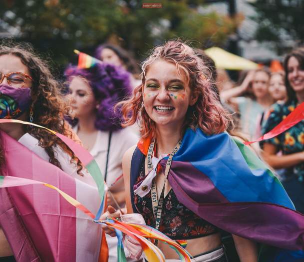 women celebrating pride parade with rainbow flags and smiling faces