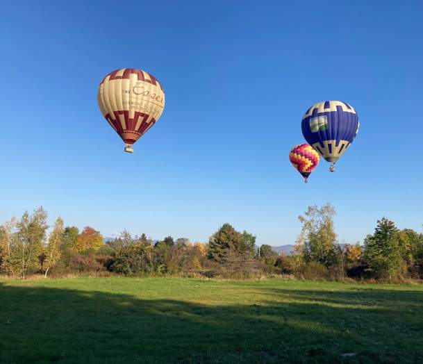 Three hot air balloons take flight in Vermont's countryside.