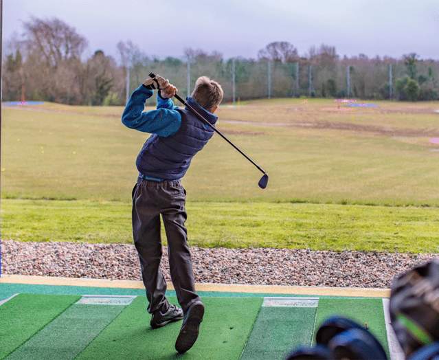 Young boy playing golf at Colin Glen driving range.